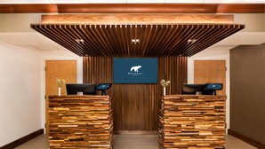 Ein Empfangsschalter mit Holzlamellenstruktur, das Logo des Bear Springs Hotels und zwei schwarze Stühle.