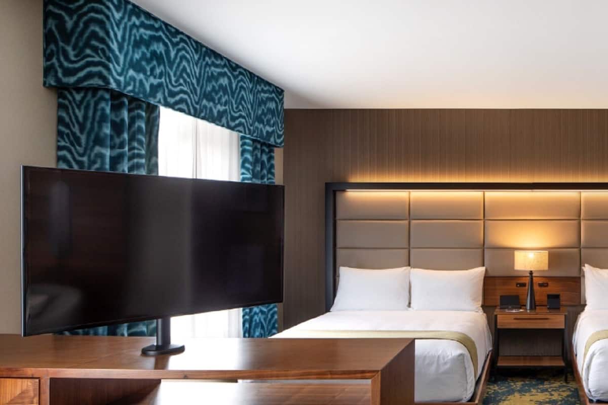 Une chambre d’hôtel avec deux lits, une télévision, un bureau, une lampe et une armoire.