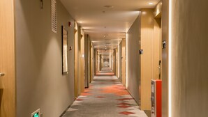 A long, well-lit hallway with a patterned carpet, doors on both sides, and a vending machine. - Borrman Hotel Canton Tower Kecun Station (Guangzhou)