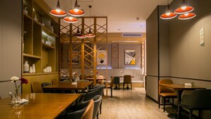 A restaurant with wooden tables and chairs, pendant lighting, and a decorative wall. - Borrman Hotel Canton Tower Kecun Station (Guangzhou)