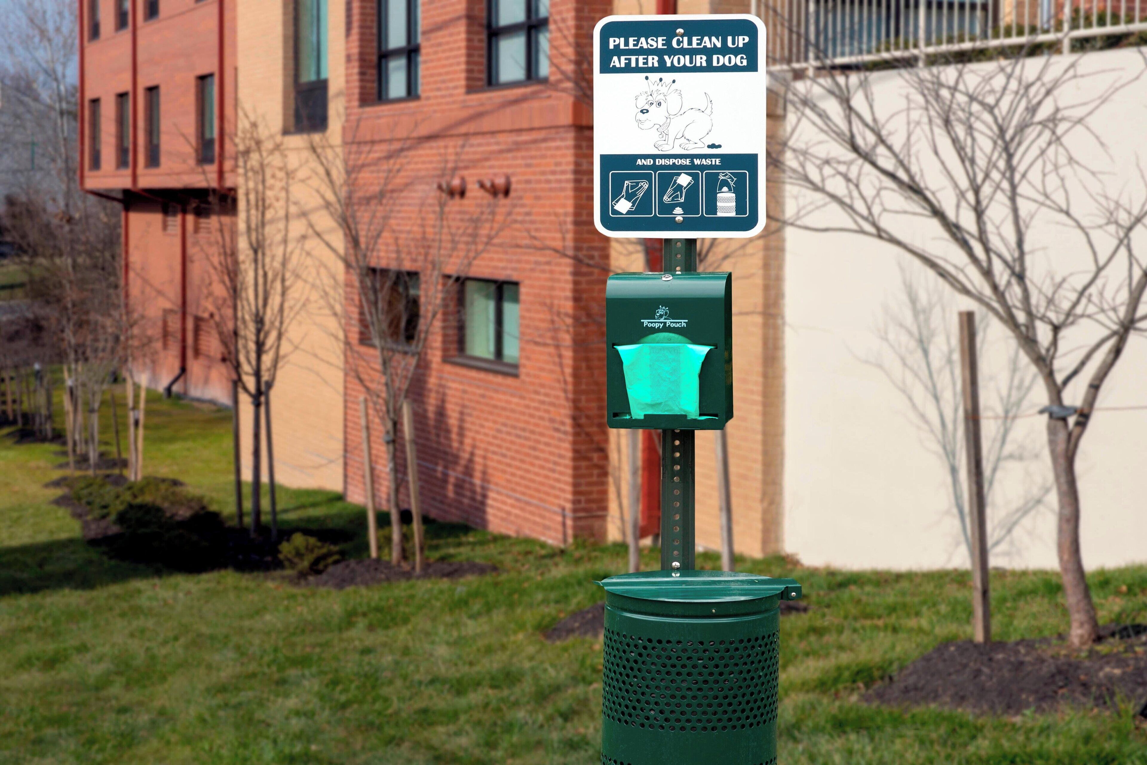 A public trash bin with a sign instructing to clean up after pets and dispose of waste.