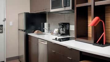 Una cocina moderna con electrodomésticos de acero inoxidable, una cafetera y una lámpara roja.