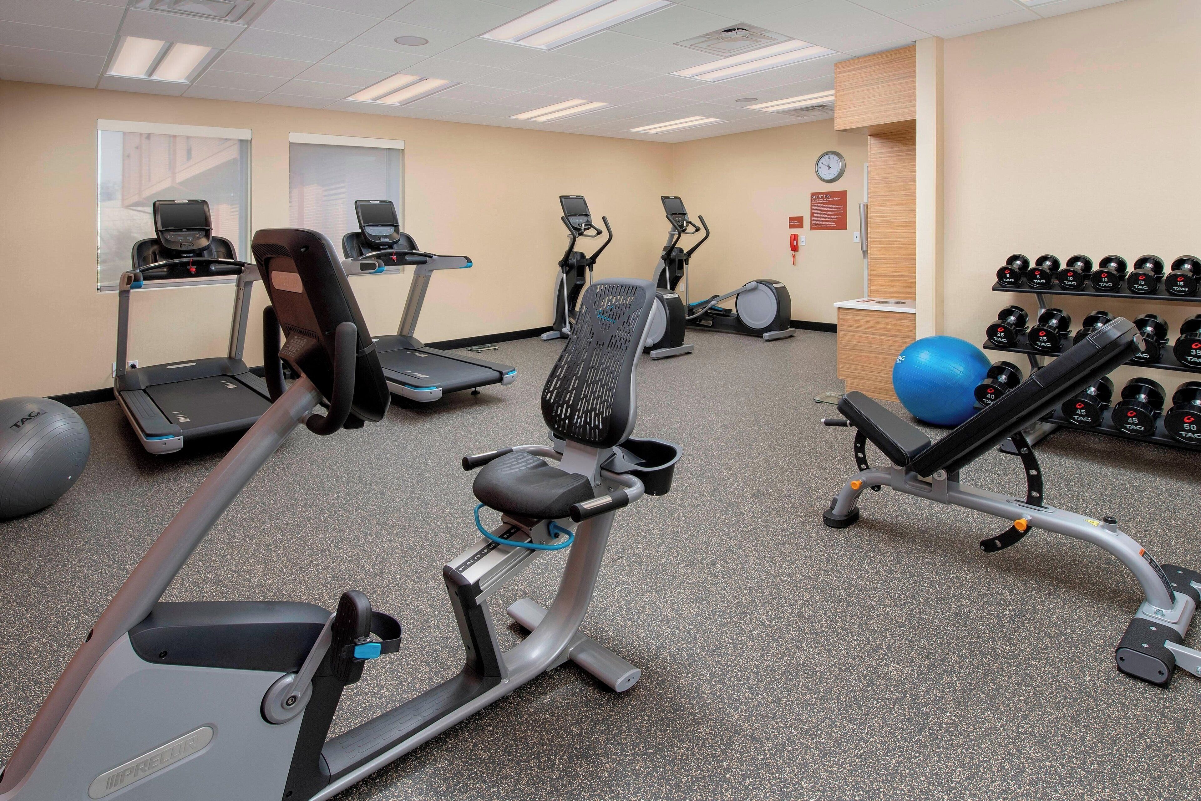 A gym with treadmills, elliptical machines, and a bench press.