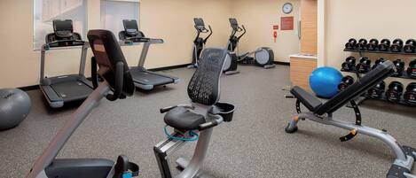 A gym with treadmills, elliptical machines, and a bench press.