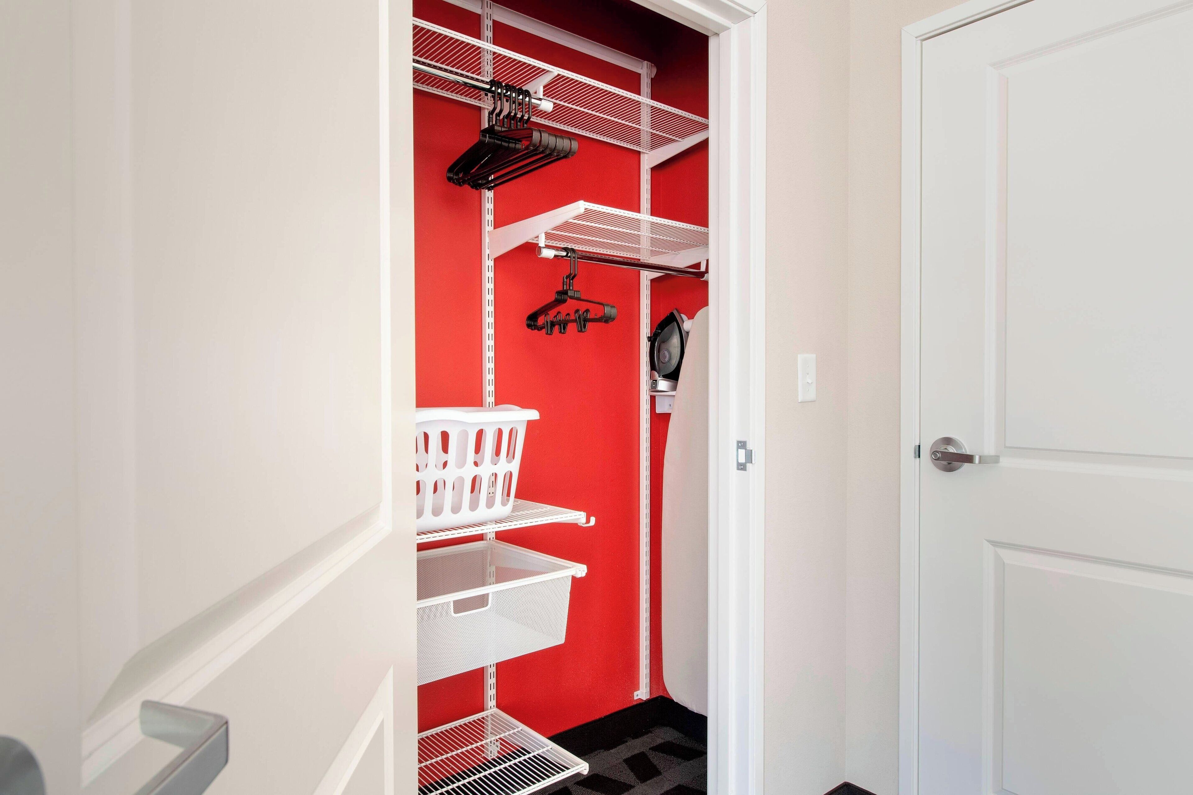A narrow hallway with white metal shelves, a white basket, and a white door.