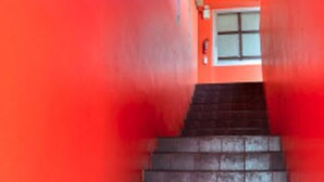 A staircase with a red wall on one side and a dark floor.