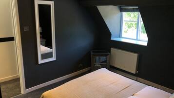 Une chambre à coucher avec un lit, une fenêtre, un radiateur et un miroir.