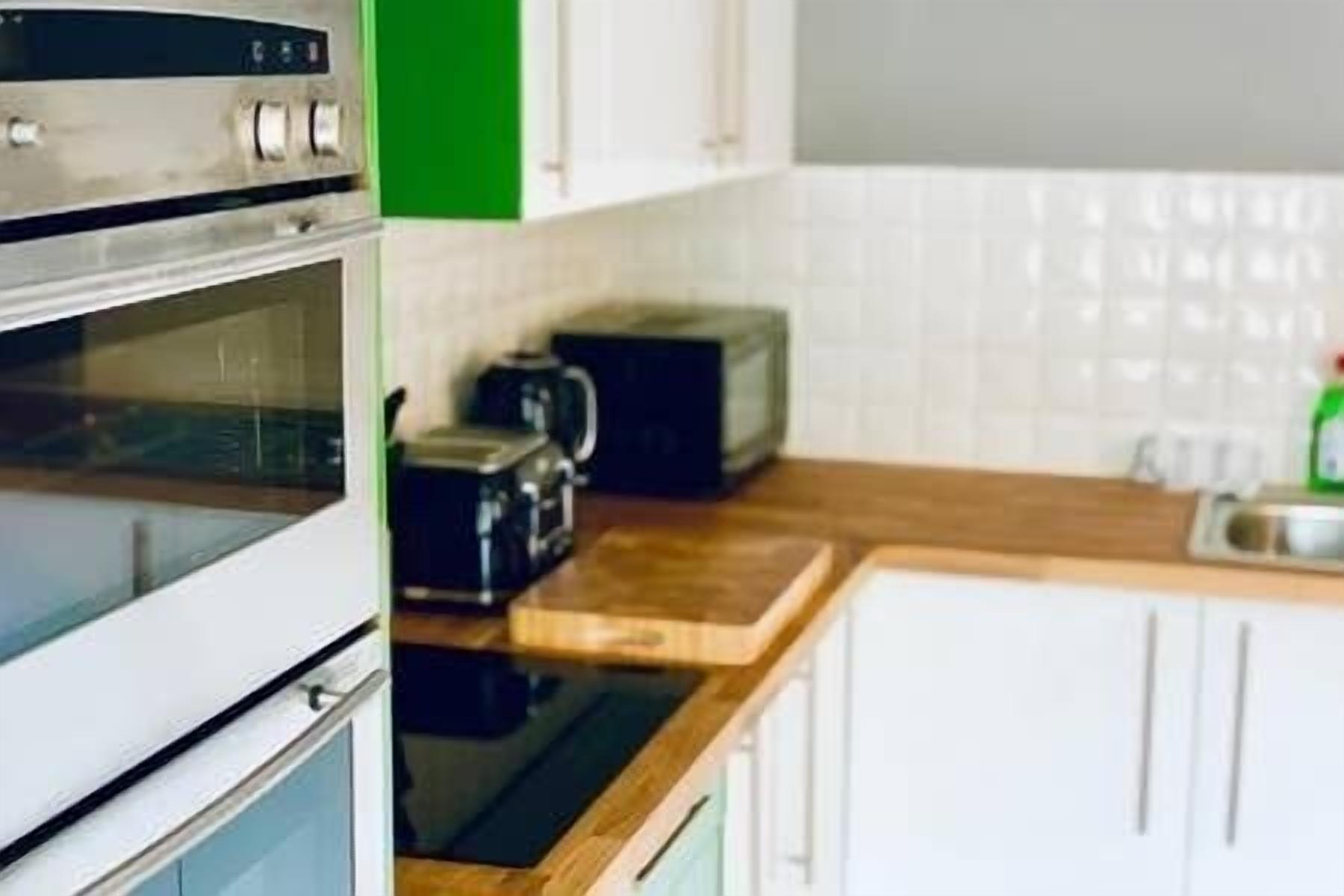 A kitchen with a built-in oven, a toaster, and a kettle.