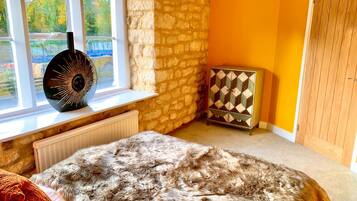 A room with a stone wall, a window with a view, a radiator, a fur rug, and a cabinet.