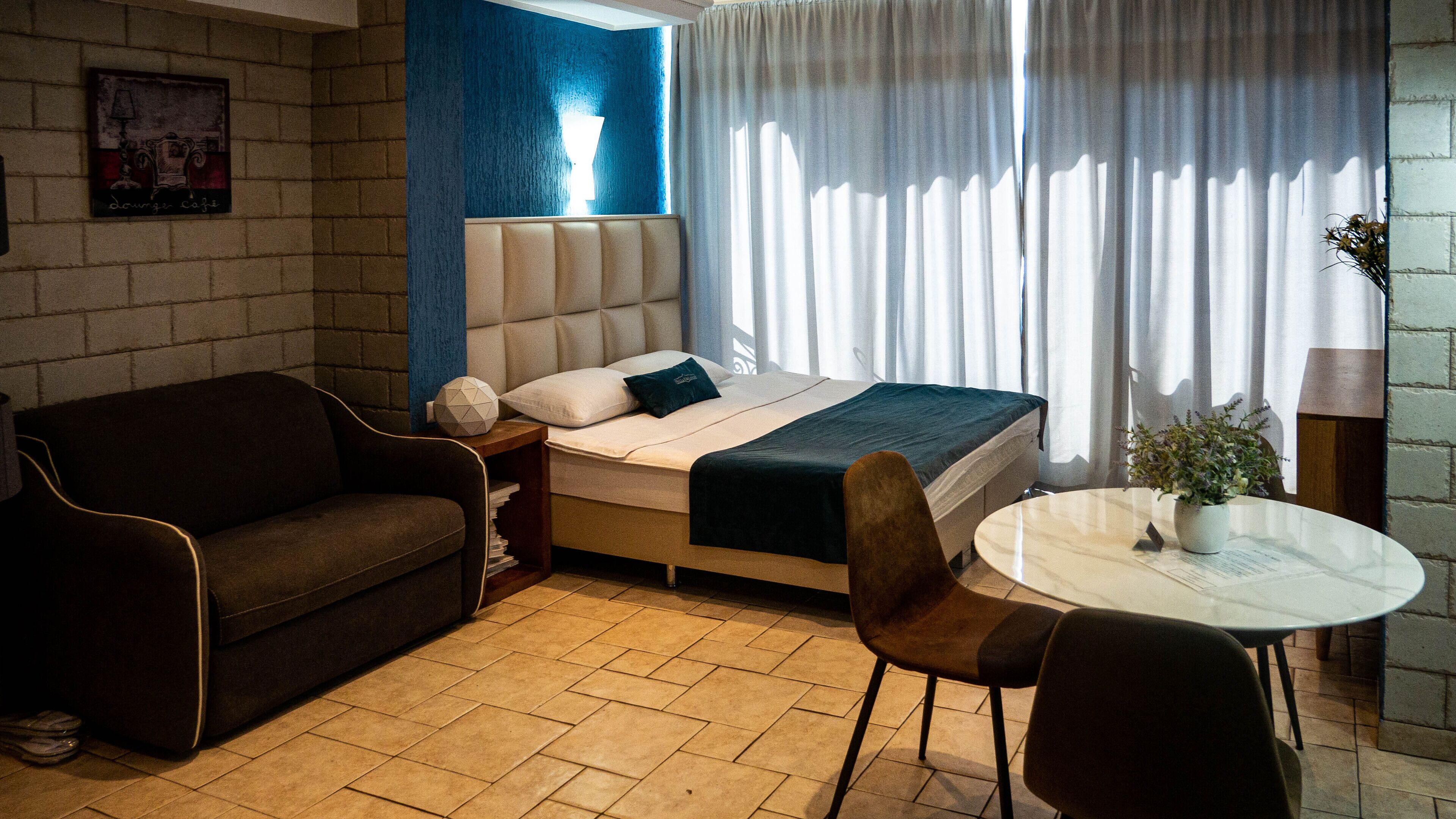 A hotel room with a bed, a sofa, a small table, and a chair.