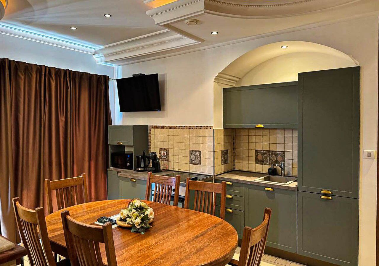 Una cocina moderna con una mesa de comedor de madera, sillas y un televisor montado en la pared.