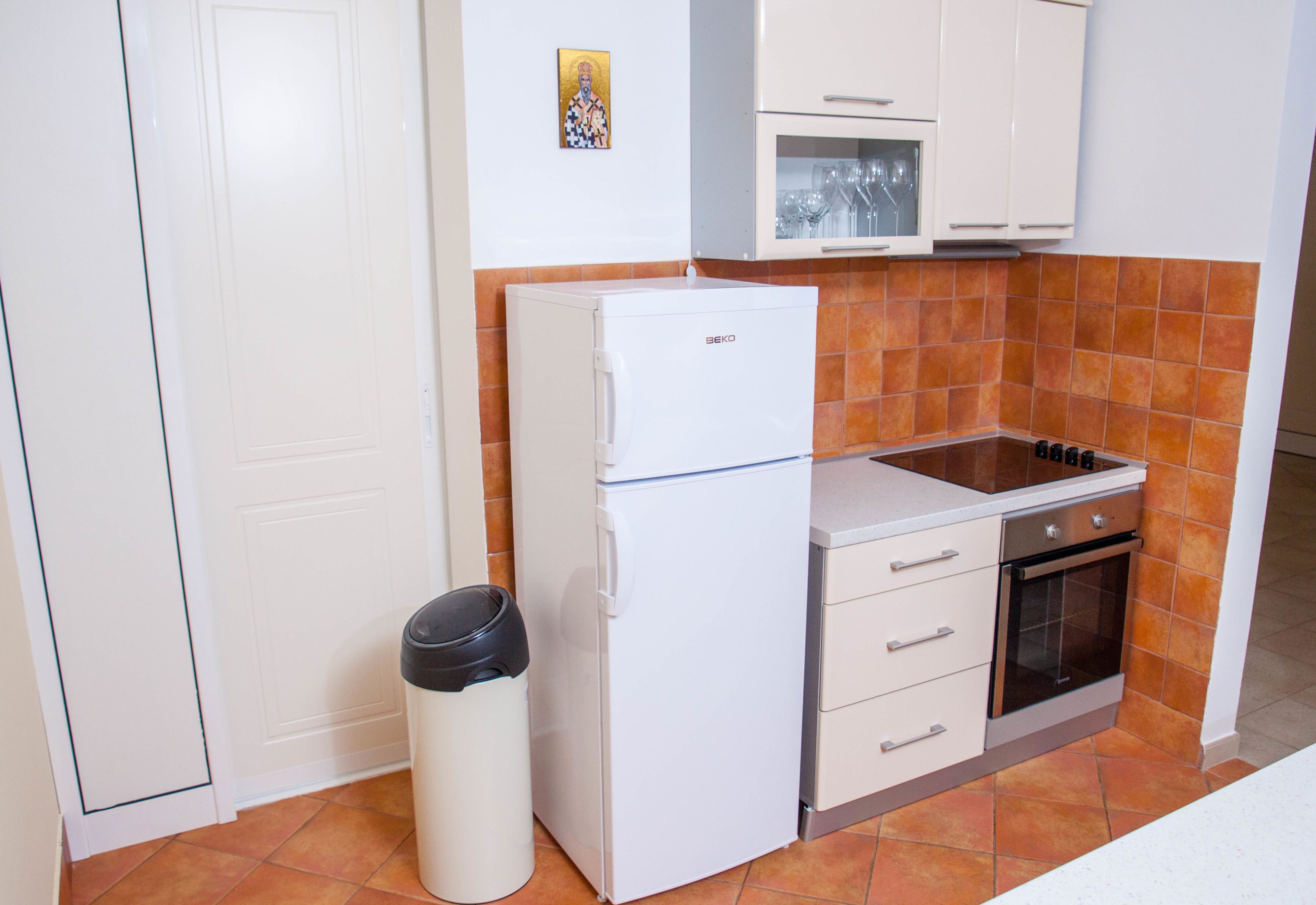 A compact kitchen with a refrigerator, oven, and sink.