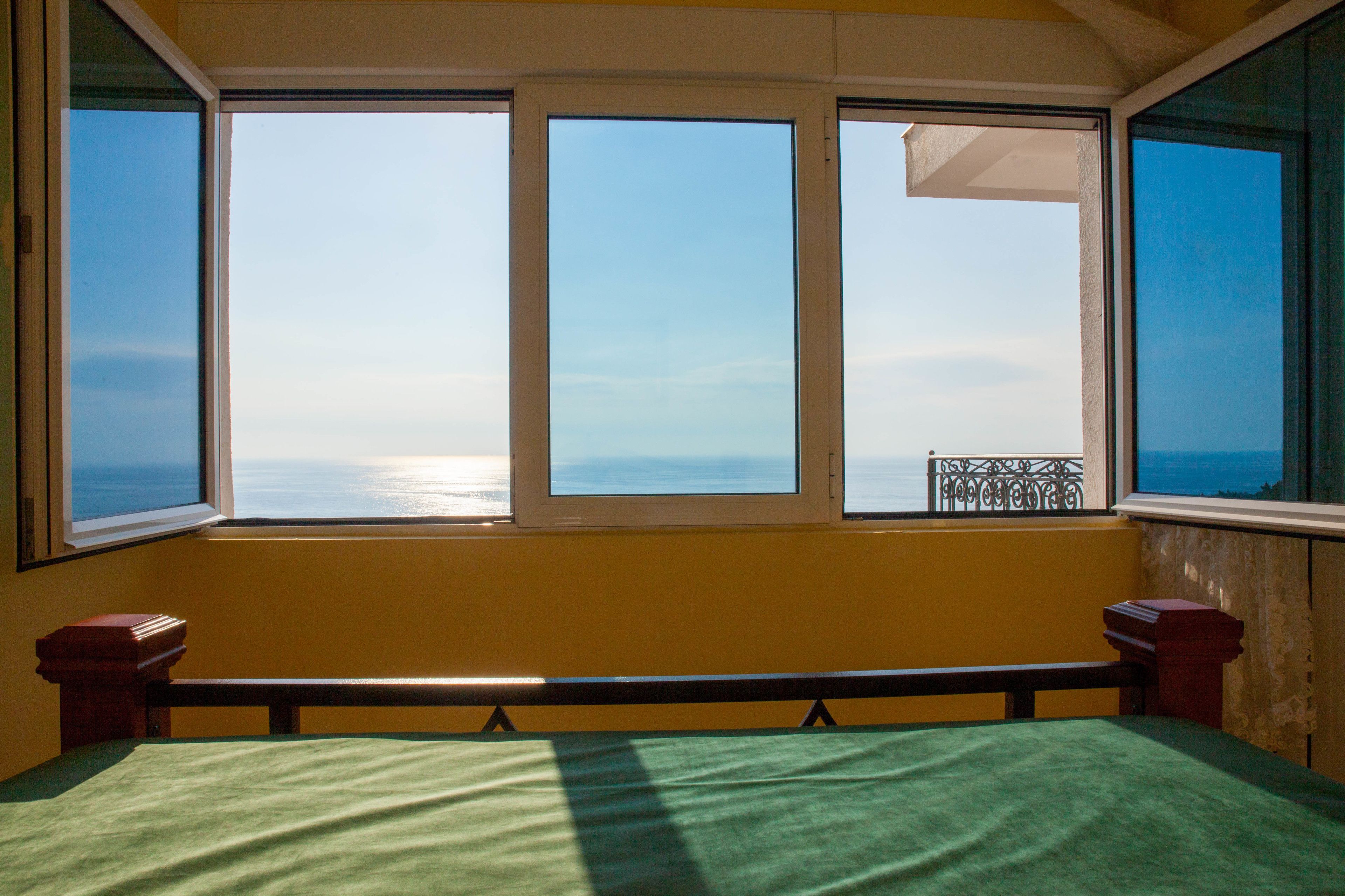 Una habitación con cama, ventana y vista al mar, además de un banco.
