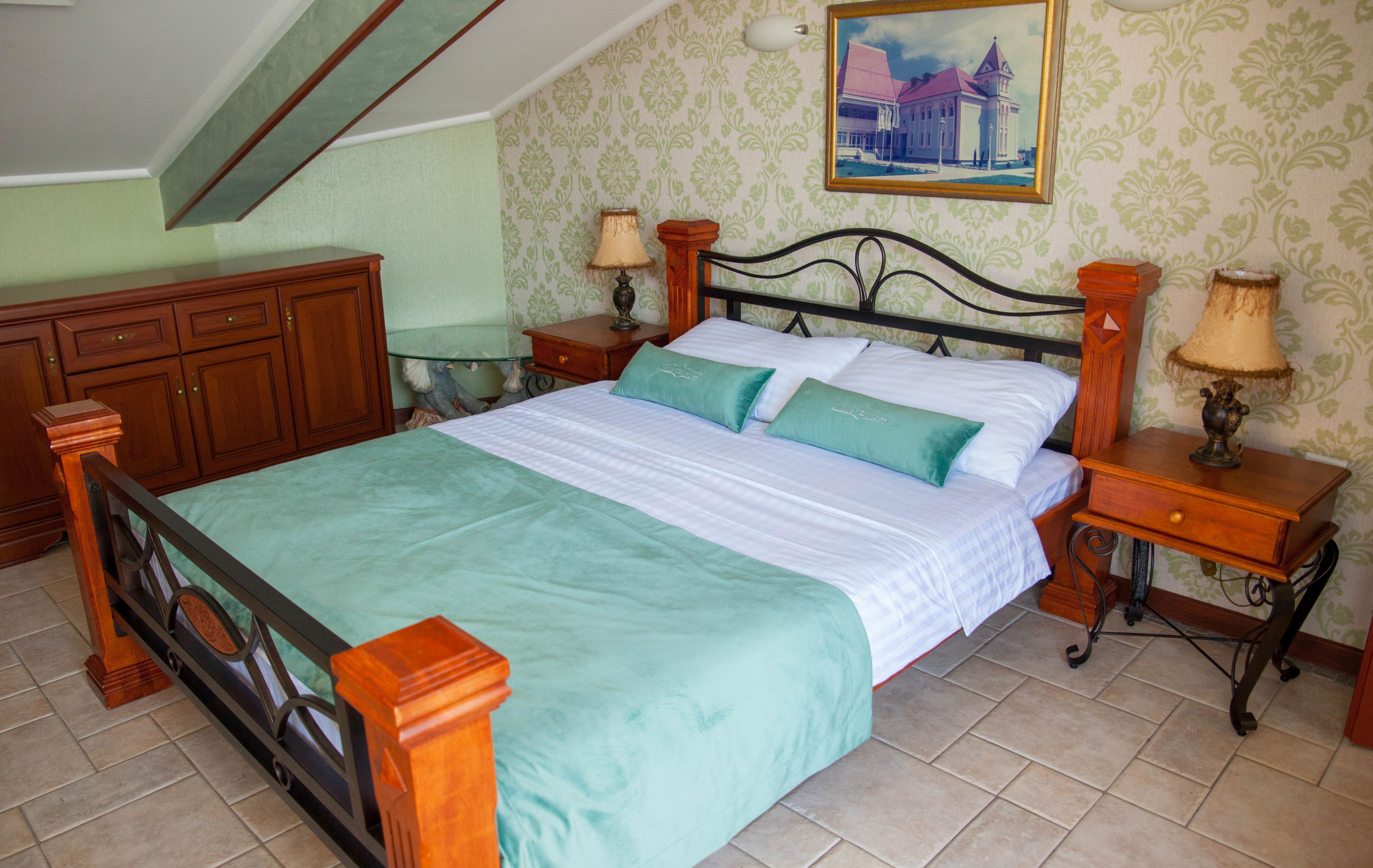 A bedroom with a bed, wooden nightstands, a dresser, and a painting on the wall.