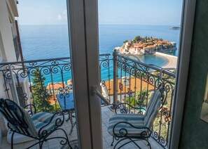 Ein Balkon mit zwei gestreiften Stühlen und Blick auf eine Küstenstadt mit Gebäuden und Strand.
