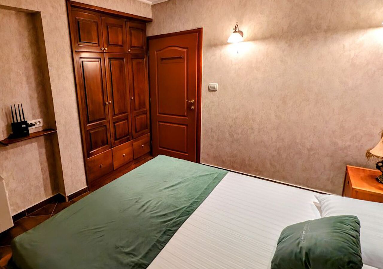 A bedroom with a bed, a wardrobe, and a nightstand.