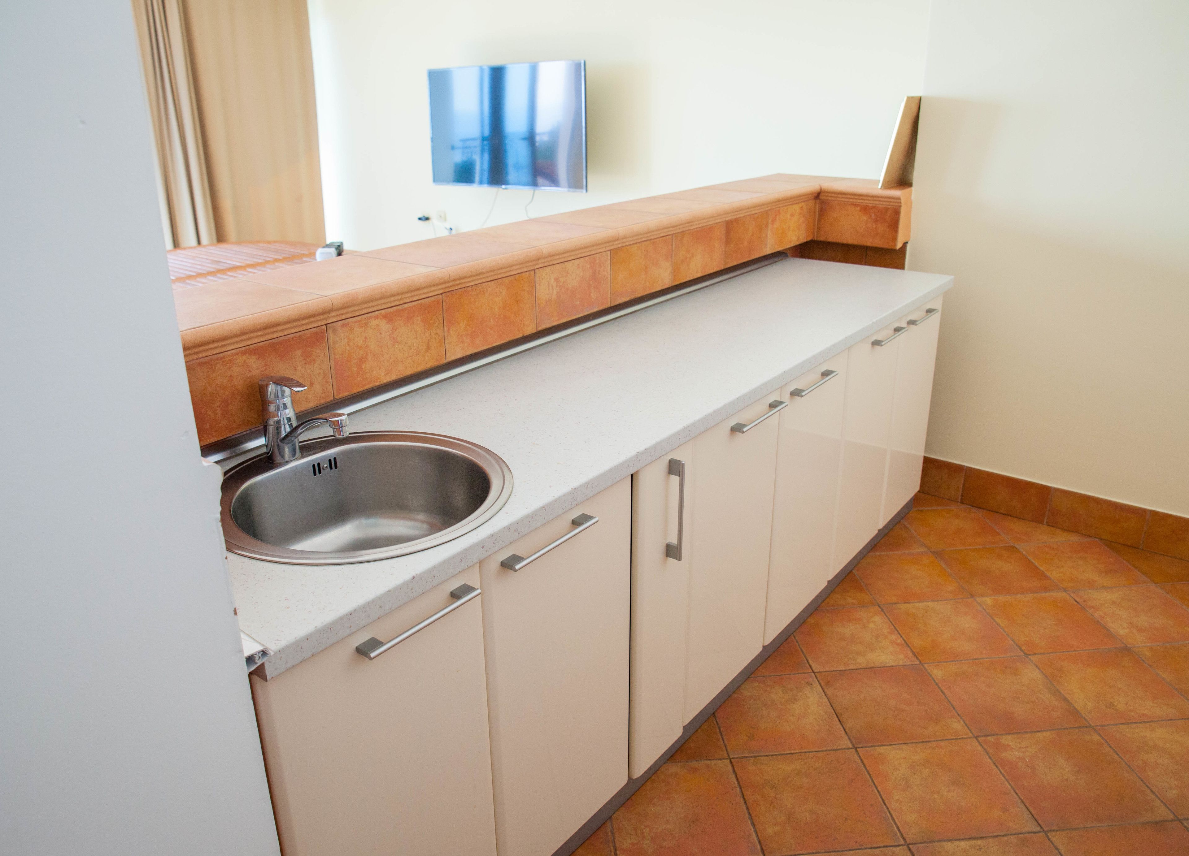 A kitchen with a sink, cabinets, and a countertop.