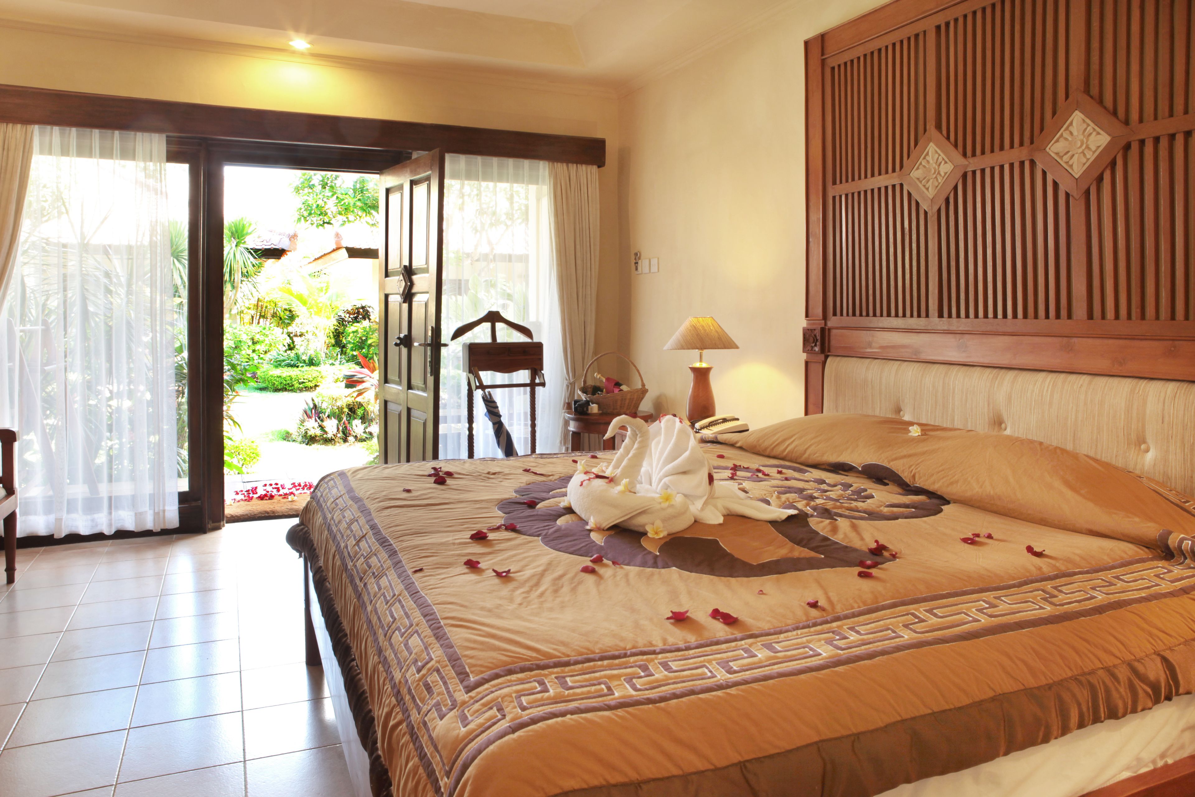 Une chambre d’hôtel avec un lit, une table de chevet, une lampe et une vue sur le jardin, accessible par une porte vitrée.