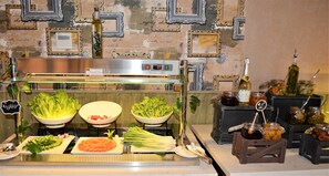 Fresh produce and condiments are neatly arranged on serving boards and in bowls, complemented by a stainless steel range hood.