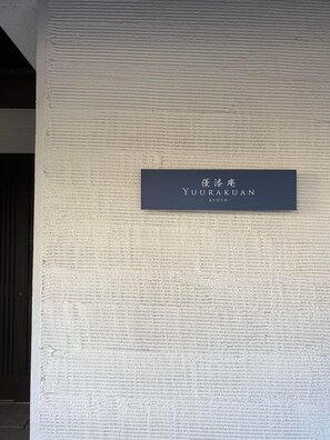 A sign on a textured wall with the name "YUURAKUAN" and "KYOTO" indicating the hotel's location. - Yuurakuan (Kyoto)