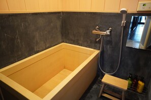 A bathtub with a wooden frame, a showerhead, and a small wooden stool. - Yuurakuan (Kyoto)