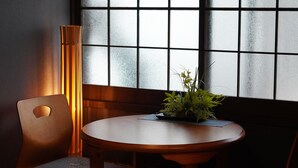 A wooden dining table with a potted plant, a chair with a cushion, and a tall floor lamp.