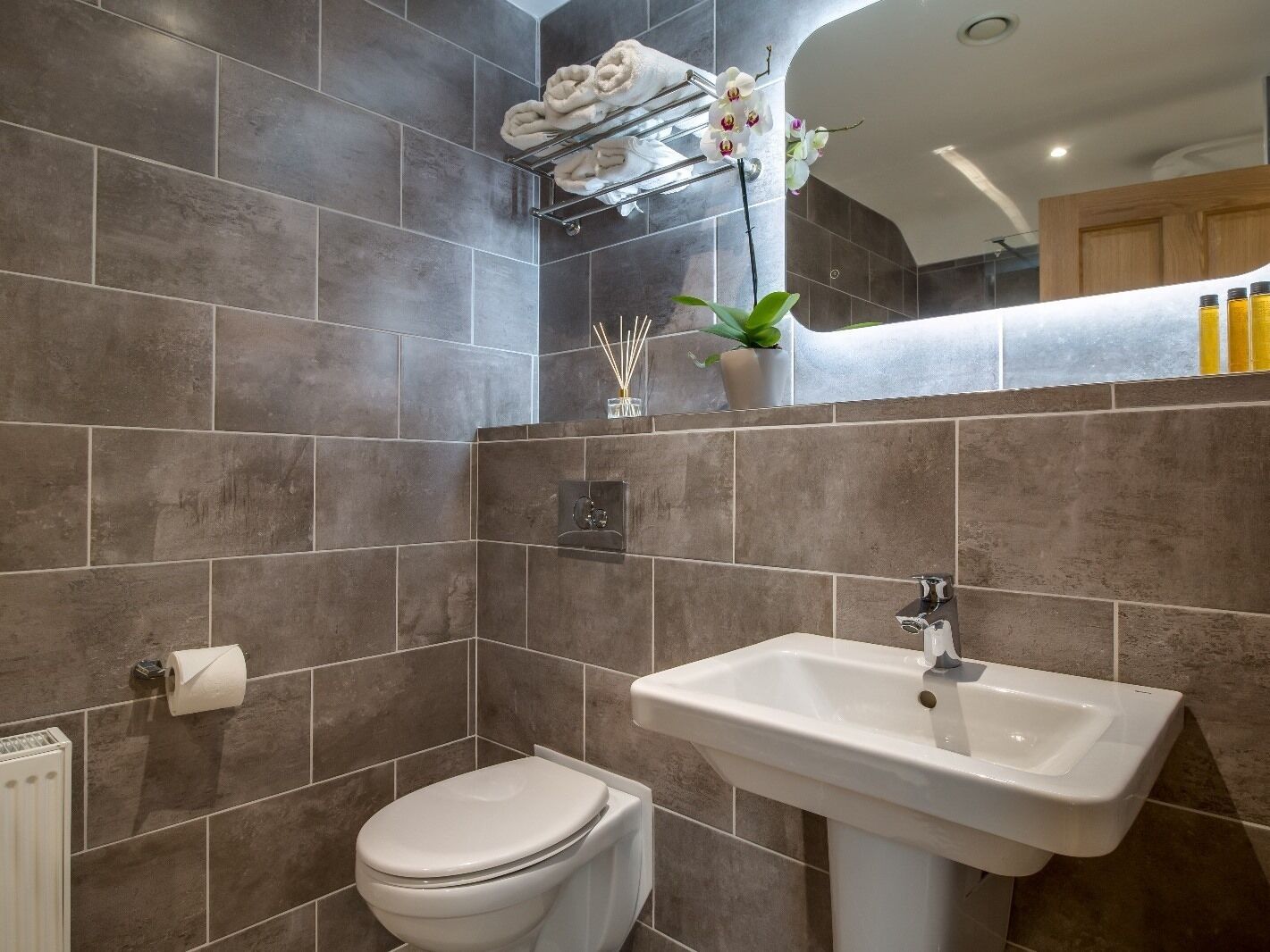 A modern bathroom with a toilet, sink, and towel rack.