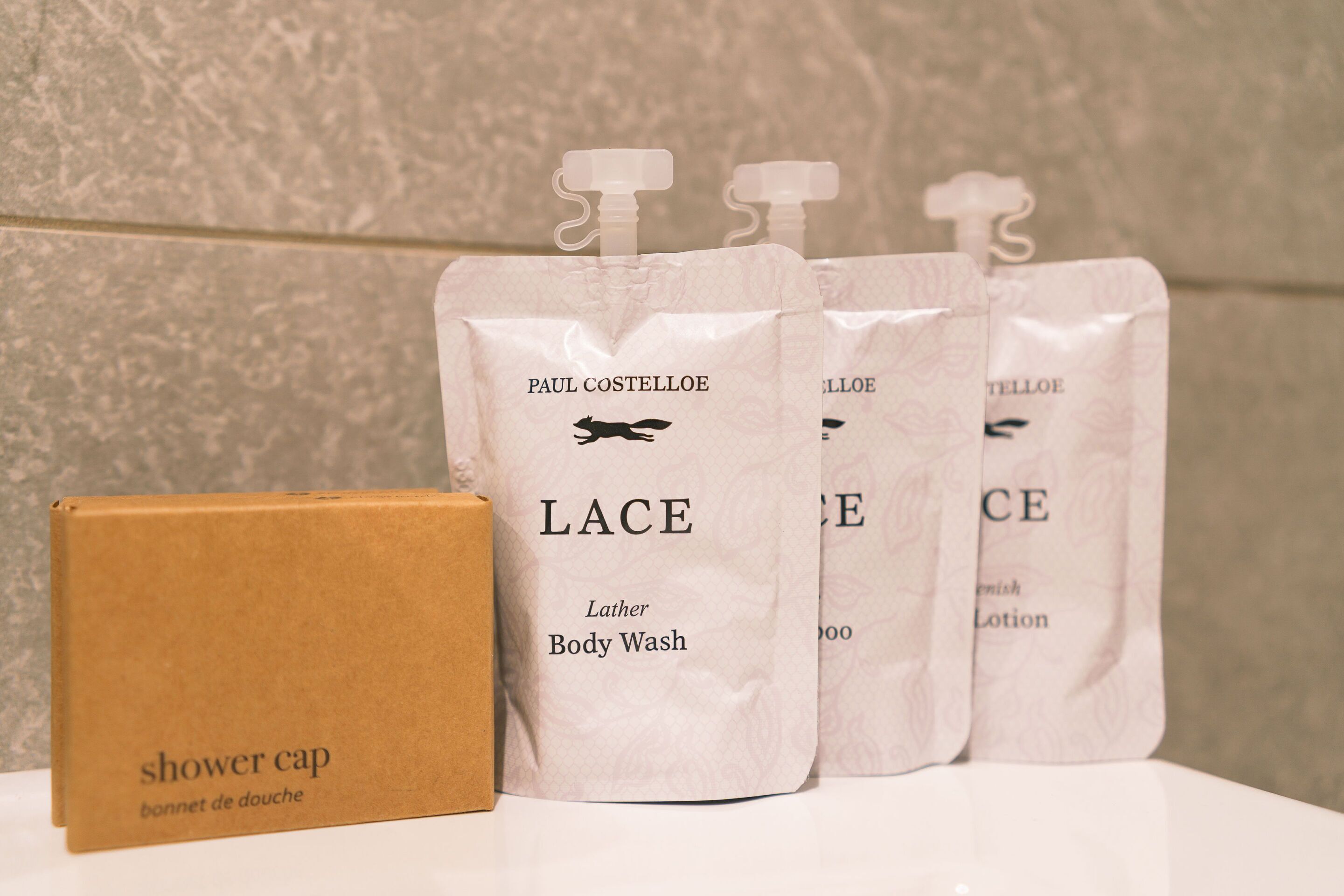 A bathroom with a shower cap and four Lather Body Wash bags.