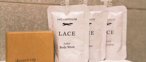 A bathroom with a shower cap and four Lather Body Wash bags.