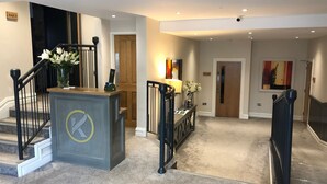 A modern hotel lobby with a reception desk, a staircase, and a bar sign. - Kingstons Townhouse (Killorglin)
