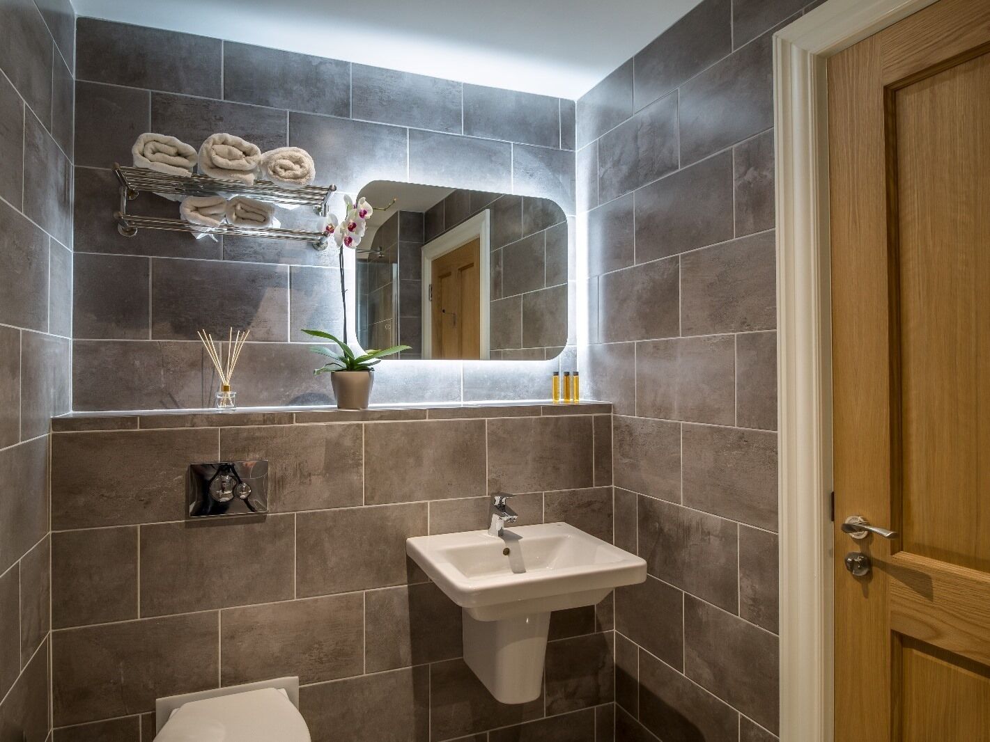 A bathroom with a sink, mirror, towel rack, and a potted plant.