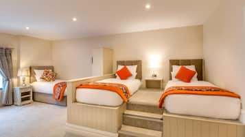 A hotel room with two beds, a small desk, and a nightstand.