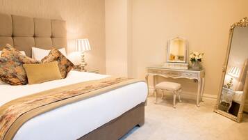 A neatly arranged bedroom with a large bed, a dresser, a mirror, and a lamp.