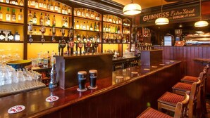 A bar area with multiple beer taps, shelves of liquor bottles, and a Guinness Extra Stout sign. - Kingstons Townhouse (Killorglin)