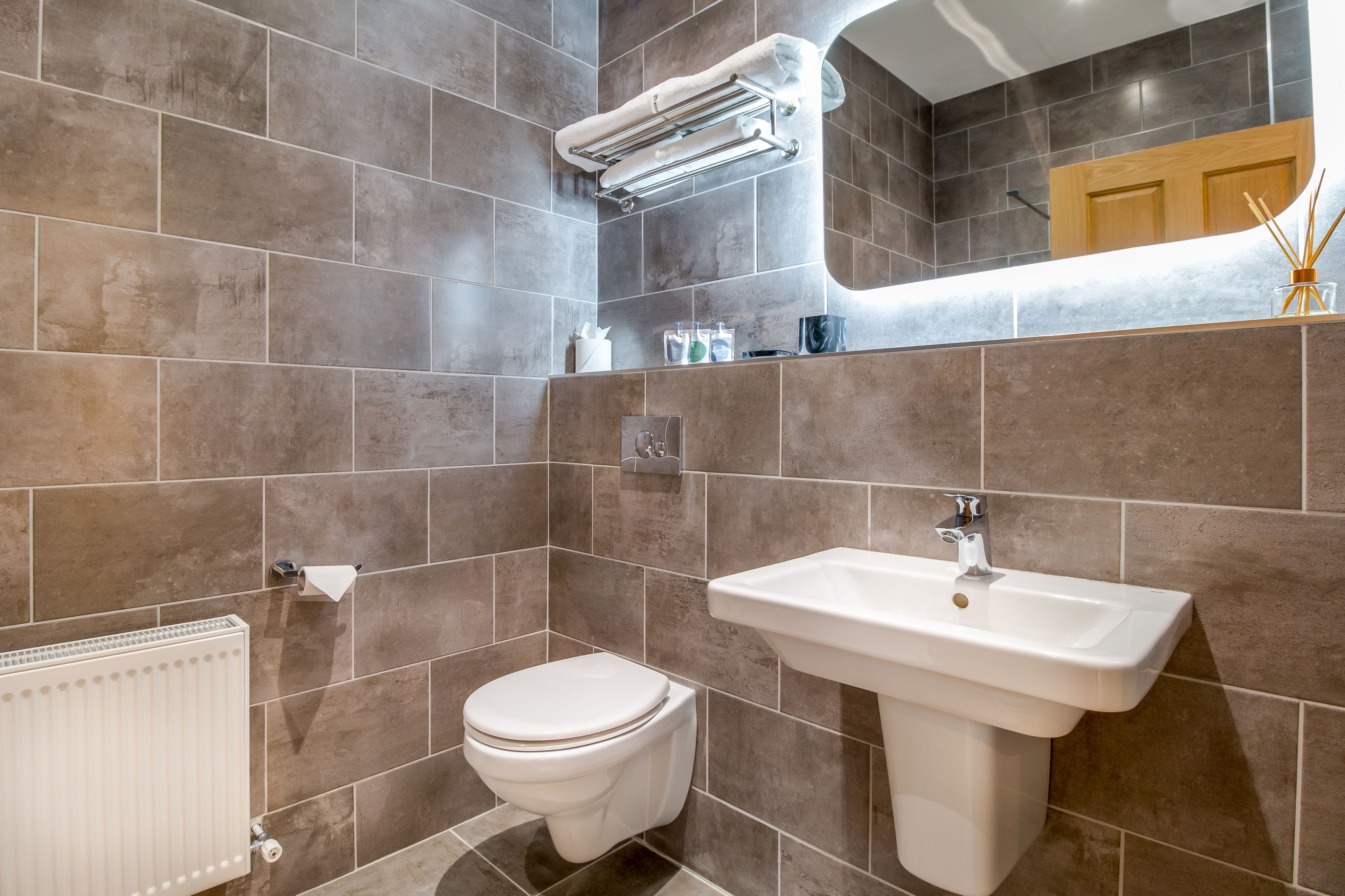 A bathroom with a toilet, sink, towel rack, and a mirror.