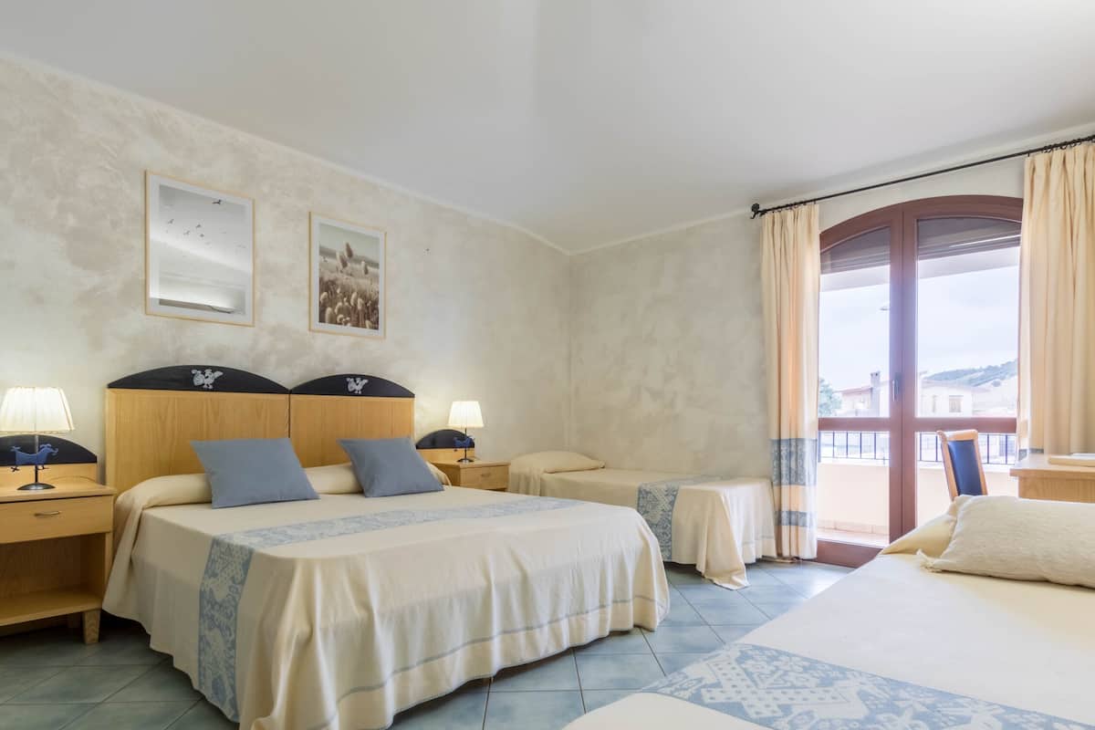 A hotel room with two beds, a large window with curtains, a flat-screen TV, and a small table.