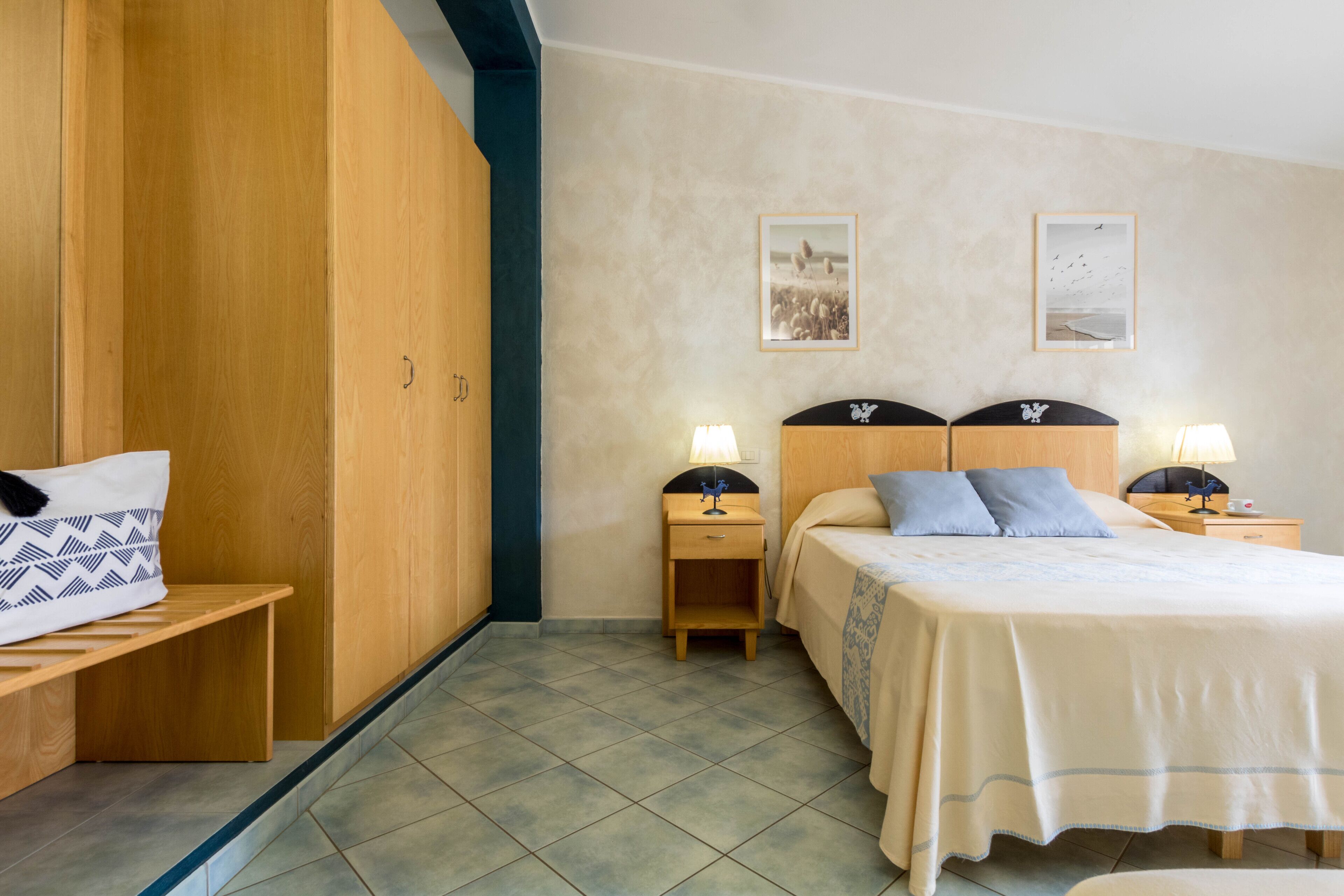 A bedroom with a bed, two nightstands, a bench, and a wardrobe.