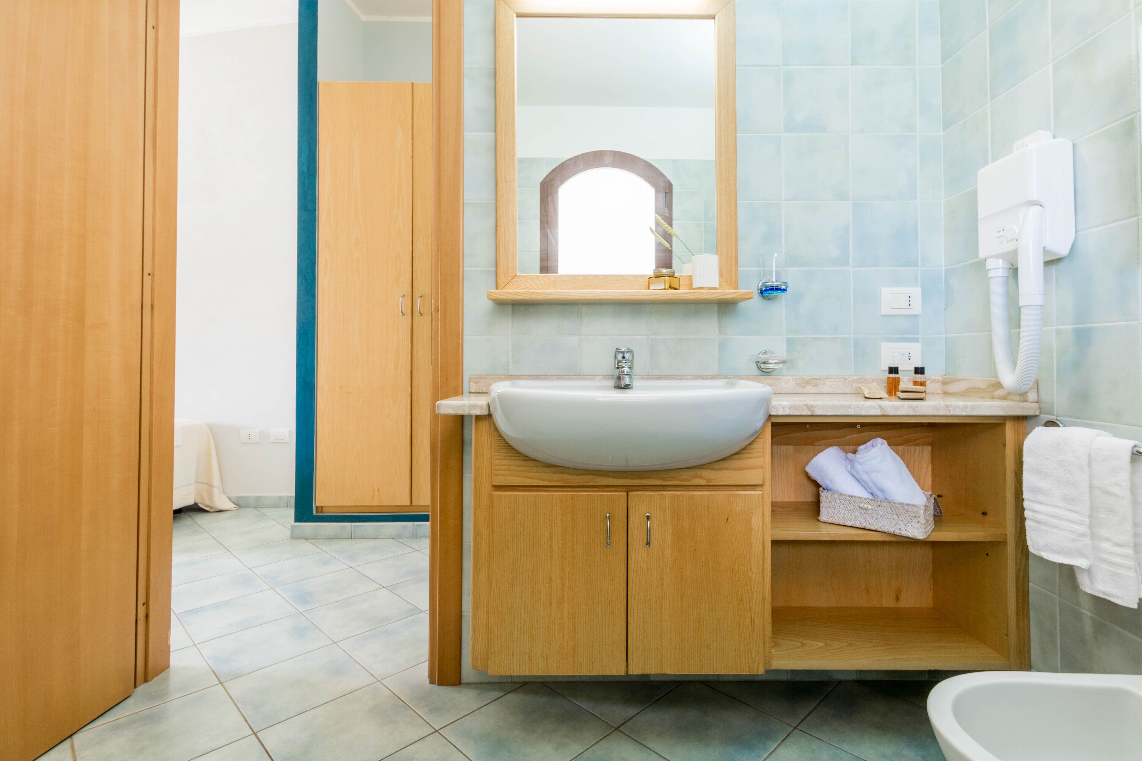 Une salle de bain avec un meuble-lavabo en bois, un lavabo blanc, un miroir et une baignoire.