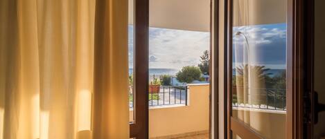 An open balcony with a view of the sea and a cloudy sky.