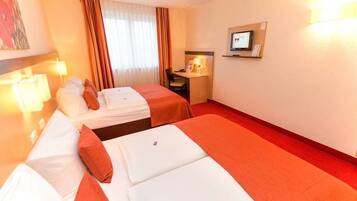 A hotel room with two beds, a desk, a chair, a TV, and a window with curtains.