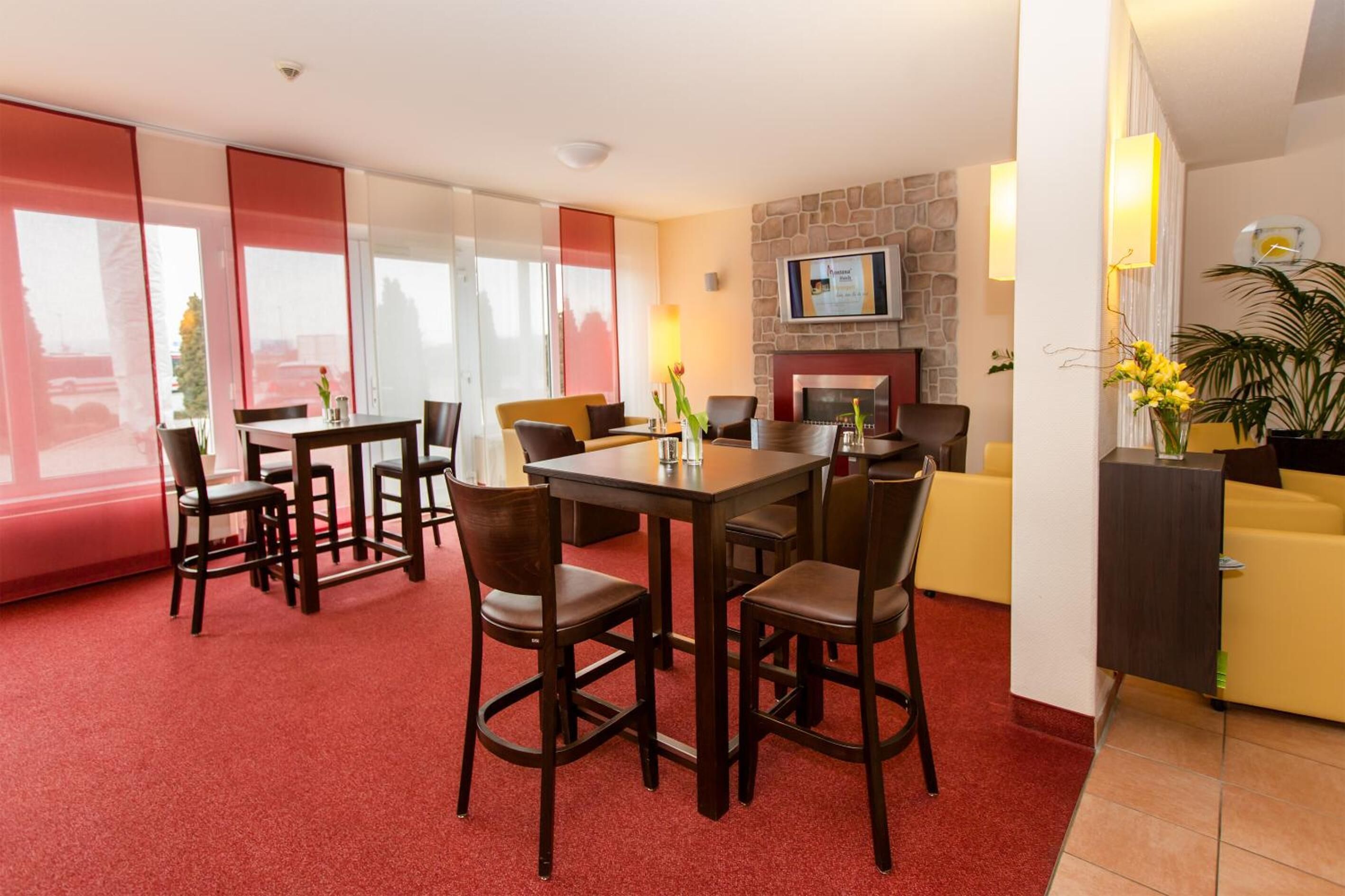A modern living room with a fireplace, a TV mounted on the wall, and a dining area with a table and chairs.