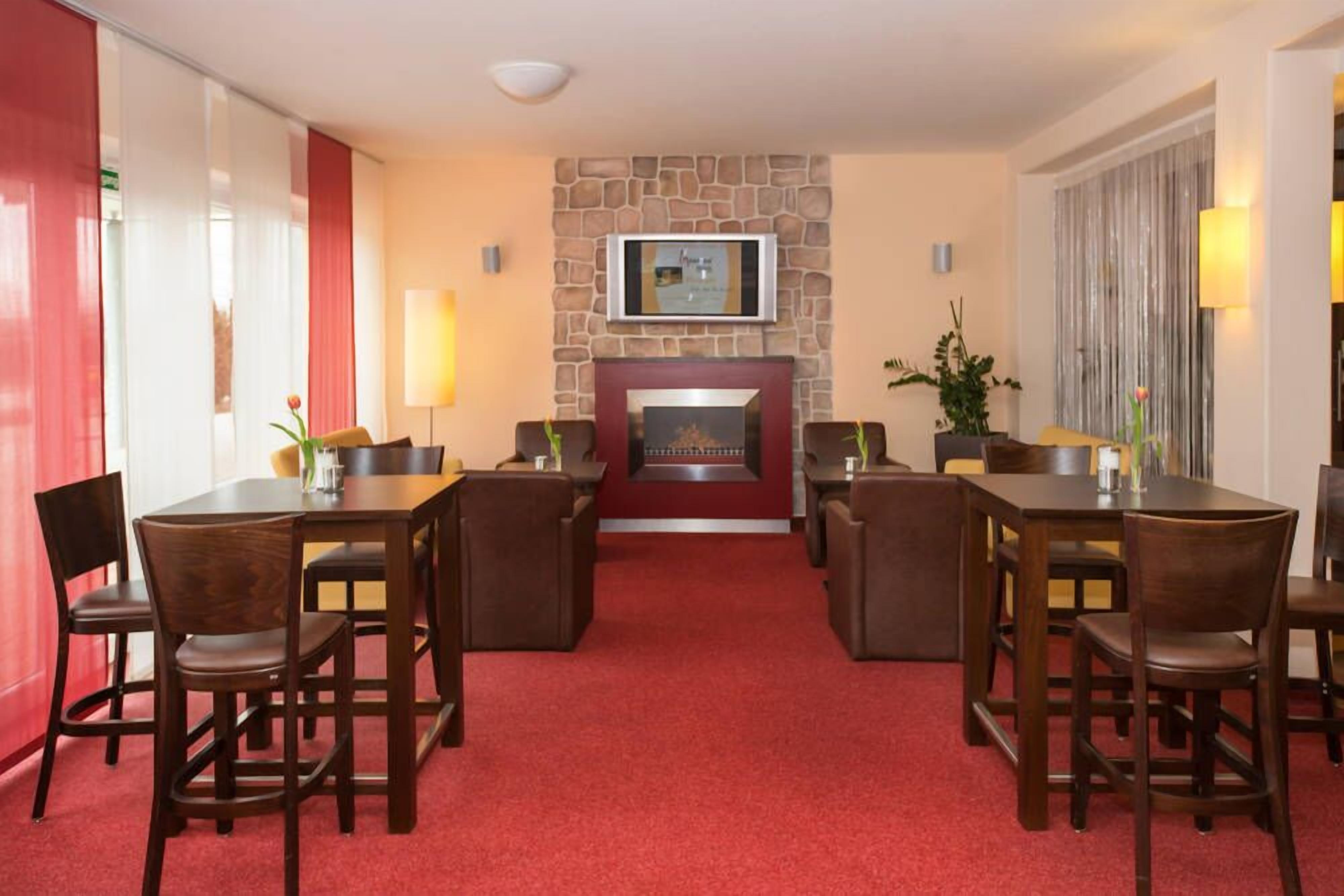 A hotel lobby with a fireplace, red carpet, and wooden furniture.