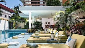 Uma área à beira da piscina com espreguiçadeiras, piscina e vegetação ao redor.