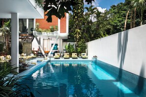 Una piscina al aire libre, sombrillas, sillones reclinables de piscina