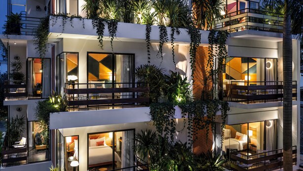 Um hotel com vários andares, varandas, janelas amplas e plantas em vasos.