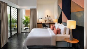 A hotel room with a large bed, a desk, and a chair. There is a ceiling fan, a lamp, and a view of the outside. - Viroth's Villa (Siem Reap)