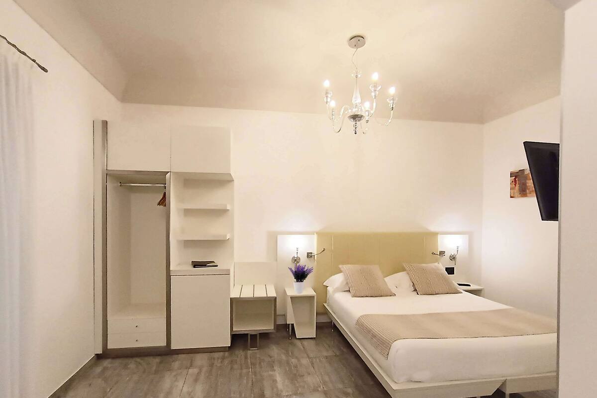 Ein Schlafzimmer mit Bett, Nachttischen, einem Kleiderschrank und einer Deckenleuchte.