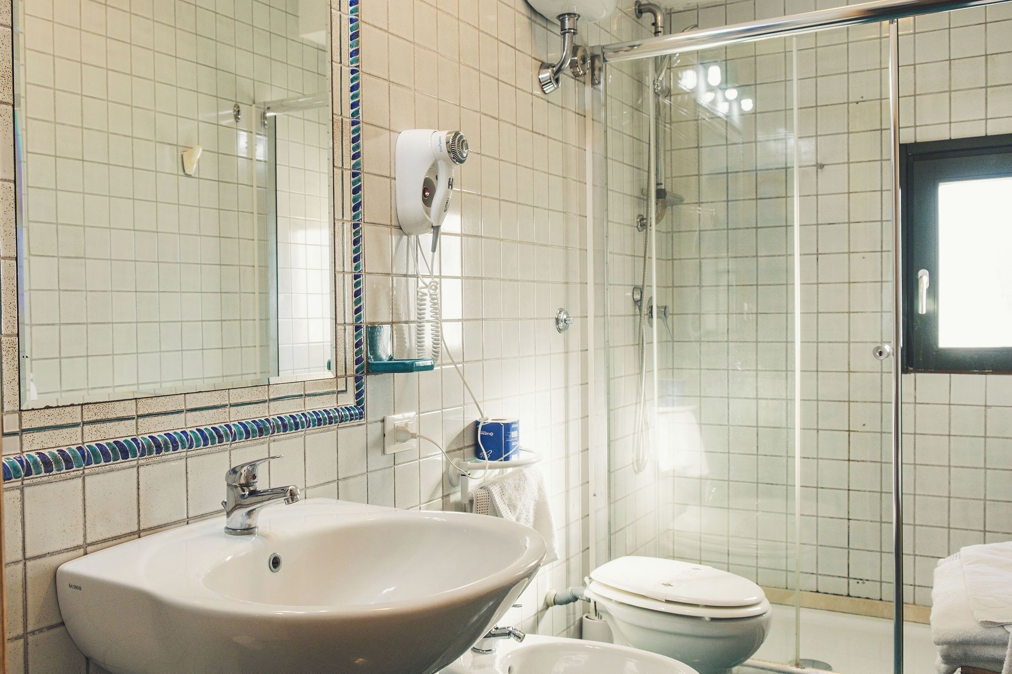 Een badkamer met een groot wastafel, toilet, douchecabine van glas en een spiegel met decoratieve rand.