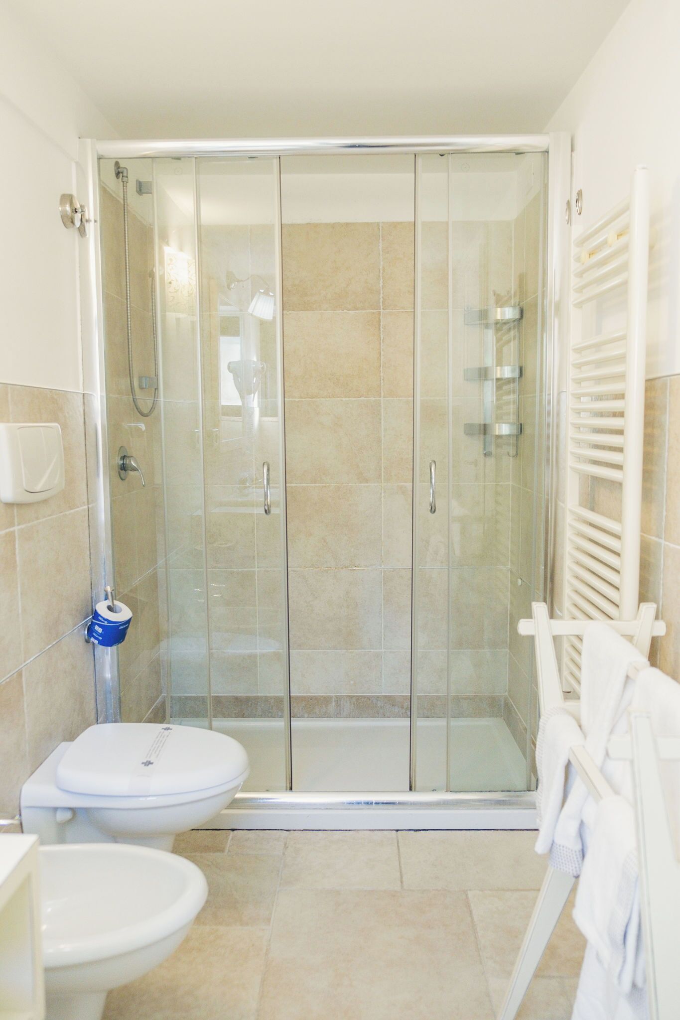 A bathroom with a glass-enclosed shower, a toilet, and a sink.