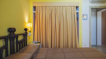 Una habitación de hotel con una cama, una mesita de noche, una lámpara y una cortina.